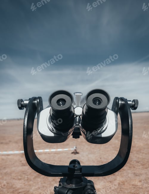 Preview: Closeup vertical shot of a public binoculars on a blue sky and dry grassland backgrounds