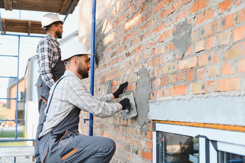Preview: Construction workers plastering brick wall during building renovation