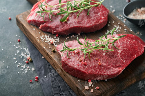 Preview: Raw beef steak. Marbled raw fresh Ribeye steak with rosemary, salt and pepper on cutting board on da
