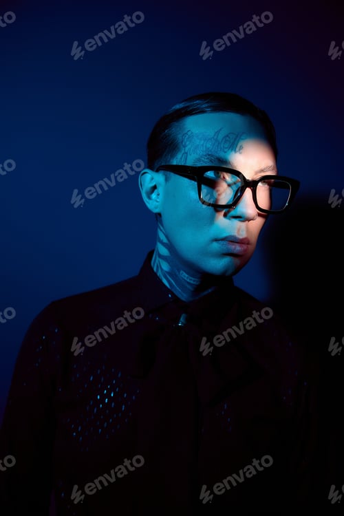 Preview: Stylish young man showcasing modern fashion against a captivating blue backdrop