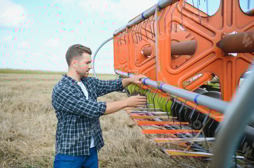 Preview: Farmer In Wheat Field Inspecting Crop. Farmer in wheat field with harvester