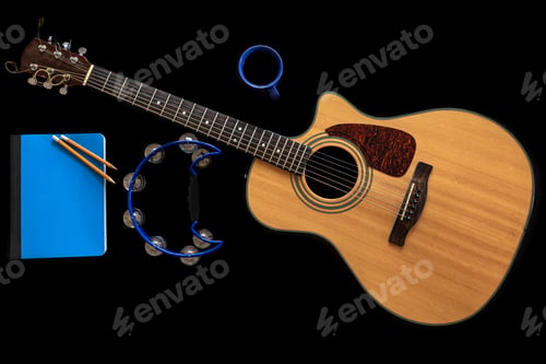 Preview: Acoustic guitar, notepad, tambourine and a cup of coffee on a black background.