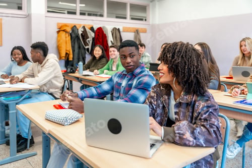 Preview: University students collaborating on project with laptop in classroom