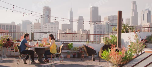 Preview: Couple Drinking Wine On Rooftop Terrace With City Skyline In Background