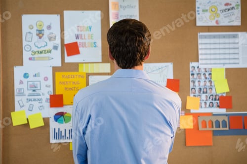 Preview: Male executive looking at the bulletin board in office