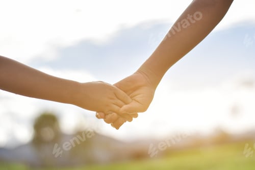 Preview: Hands of two child holding each other on field. concept of mutual assistance and friendship