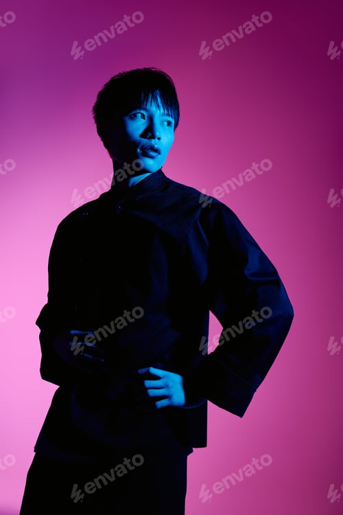 Preview: Handsome stylish asian man poses confidently against a vibrant pink and blue backdrop