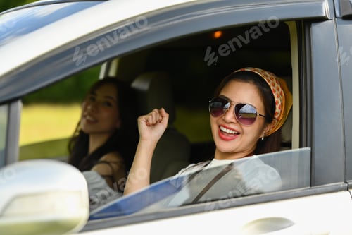 Preview: Cheerful female friends singing and dancing in car on road trip, enjoy holidays together