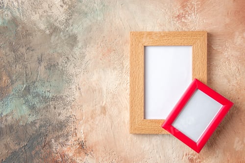 Preview: Top view of brown and red photo frames hung on top of each other on mix color wall with free space