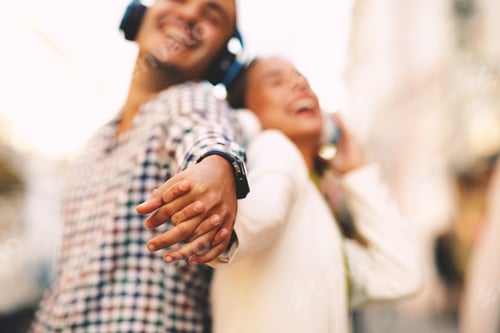Preview: Happy young couple dancing on the street and listening to music through headphones