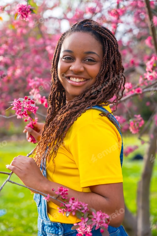 Preview: Young african woman next to pink floral tree