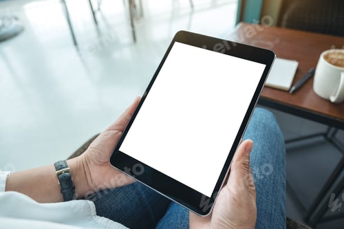 Preview: Mockup image of a woman sitting and holding black tablet pc with blank white desktop screen in cafe