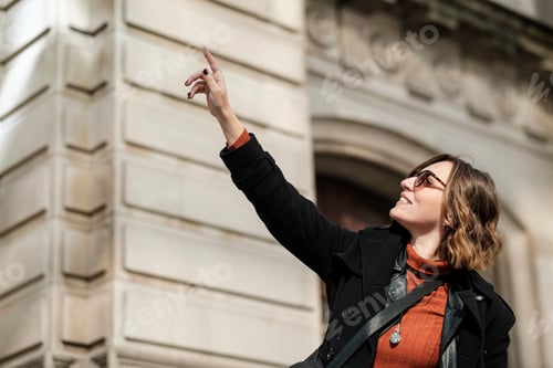 Preview: Beautiful tourist woman point a historical building.