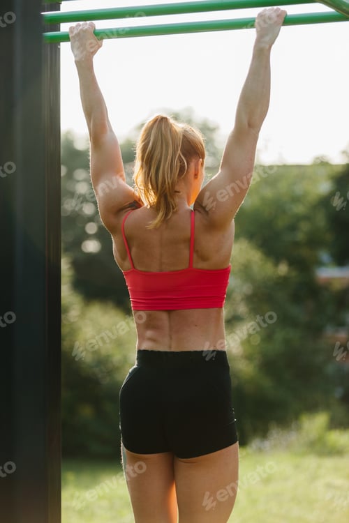 Preview: Woman exercising outdoors doing pullups