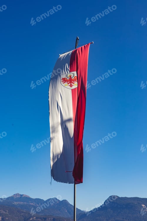 Preview: A vertical flag with a red and white design featuring an eagle emblem against a clear blue sky