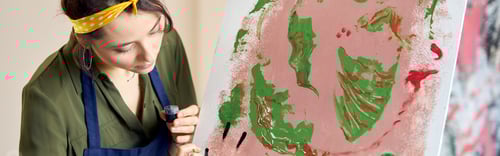 Preview: Creative young woman occupied in painting abstract picture, applying paint on canvas with fingers