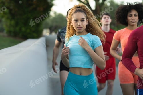 Preview: Happy group of various men and women, doing physical training outdoors. - focus on Hispanic women -