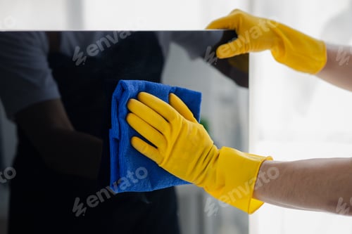 Preview: Person cleaning room, cleaning worker is using cloth to wipe computer screen in company office room.