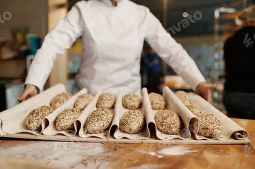 Preview: Baker preparing sweet buns pastries with sesame seeds