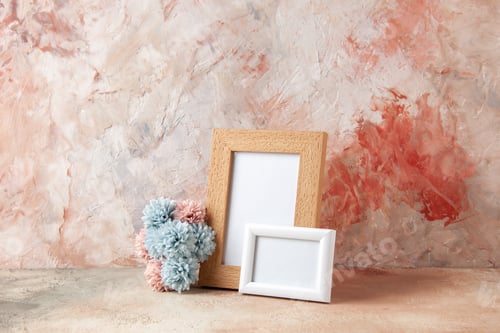 Preview: Front view of empty wooden photo frames standing on table and flower on nude color background