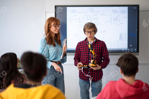 Preview: College student presenting his builded robotic toy to young science teacher at robotics classroom at