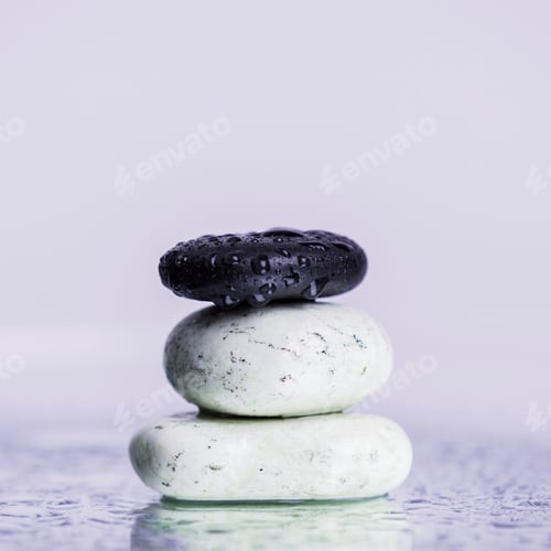 Preview: Close up view of zen stones in water drops on wet glass isolated on purple