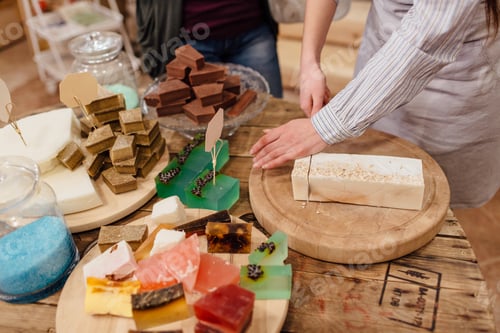 Preview: Shop assistant cutting bars of natural soap for customer in package free store.
