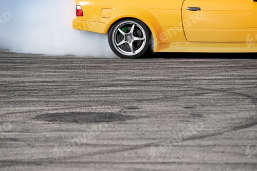 Preview: yellow sport car drifting on gray speed tarmac track with smoke coming out of the back tire wheel
