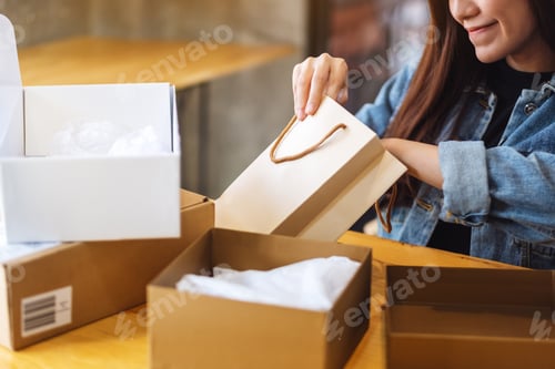 Preview: A woman opening and looking inside shopping bag at home for delivery and online shopping