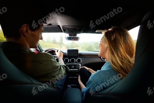 Preview: couple from behind sitting in car together on road trip