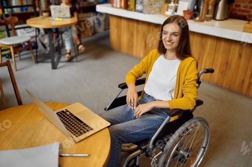 Preview: Disabled female student in wheelchair using laptop