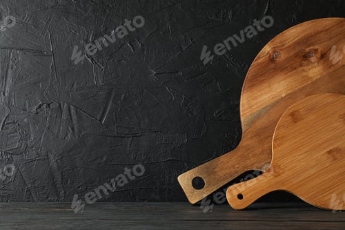 Preview: Cutting boards on wooden table against black background, space for text