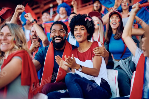 Preview: Happy black couple cheering while speciating a sports championship at the stadium.