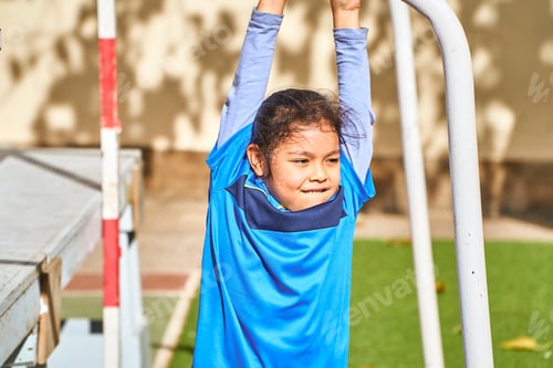Preview: latin girl football player in a sport suit balancing on a soccer goal