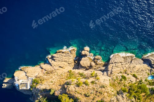 Preview: Top view on a lighthouse standing on the rocky hill near the sea with blue turquoise water in