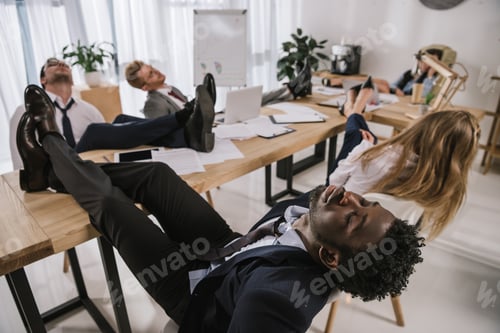 Preview: exhausted businesspeople sleeping in conference hall with feet on table