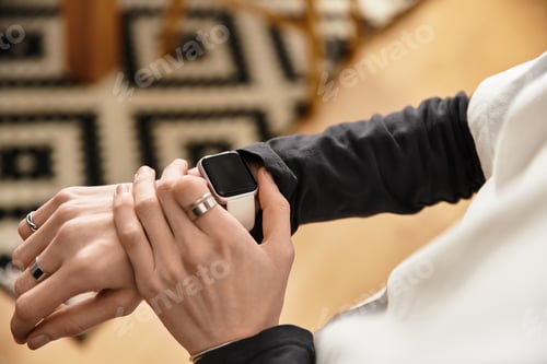 Preview: Young man enjoys moments of leisure at home while checking smart watch in cozy attire