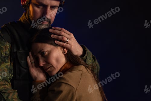 Preview: Sad woman hugging her military husband and saying-goodby to him before going to army on black