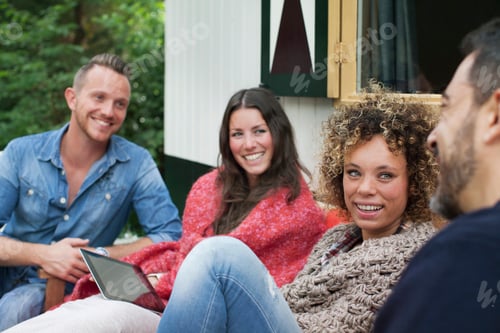 Preview: Four adult friends chatting outside cabin