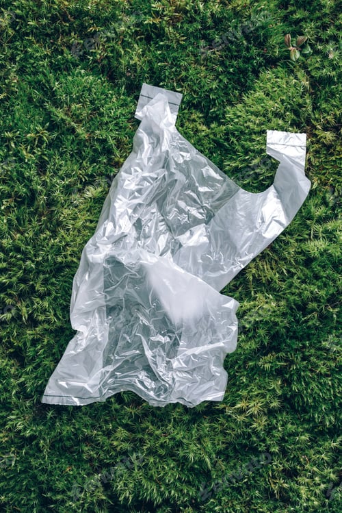 Preview: Disposable plastic bag on green moss, grass background. Pollution problem concept. Top view. Copy