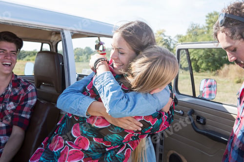 Preview: Joyful family moment with a mother embracing her child near a vintage van on a sunny day.