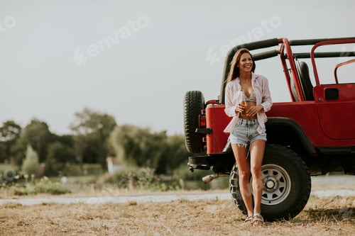 Preview: Young woman relaxing by the car on the lakeside