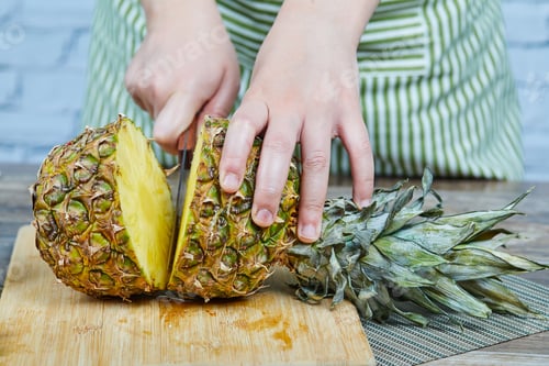 Preview: Man slicing a fresh pineapple on a wooden cutting board