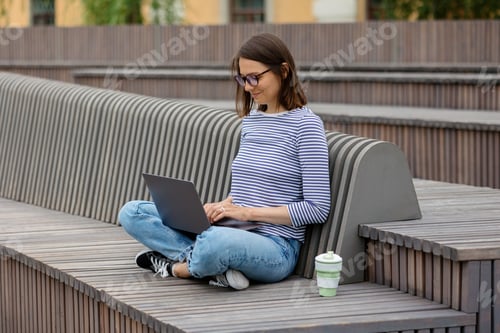 Preview: confident woman with laptop works outside in good weather, woman typing and drinking coffee