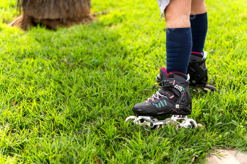 Preview: Girl wearing inline skates standing on green grass in a park
