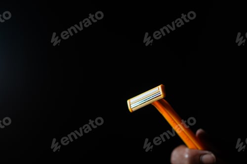 Preview: Close-up of hand holding orange razor