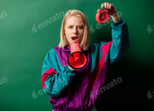 Preview: woman in 90s style punk jacket with loudspeaker and alarm clock on green background