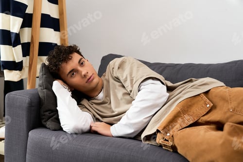 Preview: Stylish teenager relaxing at home with a thoughtful expression and casual attire