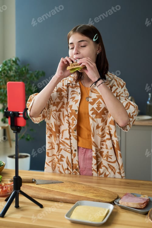Preview: Teen Girl Tasting Sandwich While Recording Cooking Video Indoors