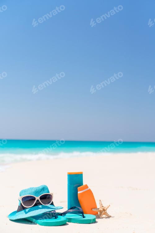 Preview: Suncream bottles, goggles, starfish and sunglasses on white sand beach background ocean